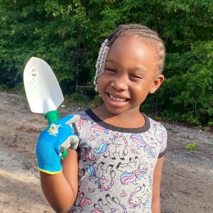 Girl holding spade smiling
