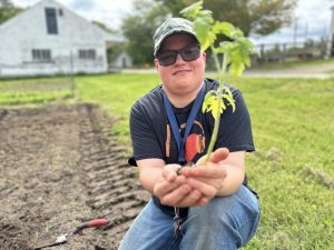 Boy showing off growing plant in field